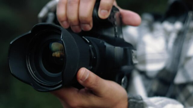Photographer preparing camera for shooting, adjusting settings and lens in a natural environment