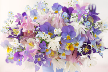 Background with a bouquet of spring and summer blue, pink, white and purple flowers, columbine, pansies, forget-me-nots. Close-up, blur, card.