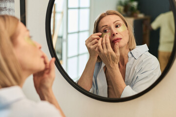 Applying Skincare Product While Looking in Mirror