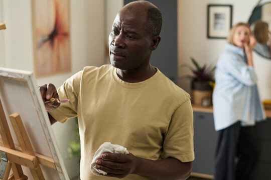Senior African American Man Painting Canvas Thoughtfully