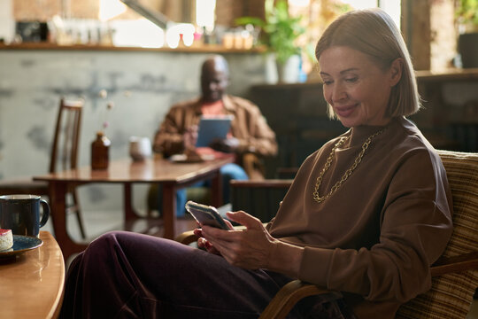 Smiling Woman Using Smartphone in Cozy Cafe Setting