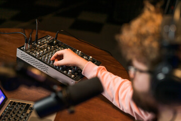 Cheerful young man recording podcast in studio. Confident man with headphones and microphone...