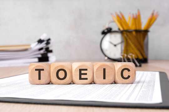 wooden cubes spelling 'TOEIC' on documents, representing business and education review