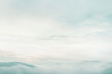 Obraz premium Serene landscape of misty mountains under a pale sky, evoking tranquility and peace
