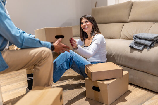 Couple unpacking cardboard boxes in new home living room