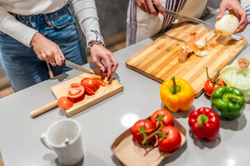 Chefs slicing tomatoes and onions, preparing ingredients for healthy meal