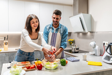 Couple preparing salad together in modern kitchen