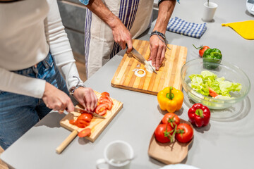 Couple slicing vegetables, preparing healthy meal in kitchen