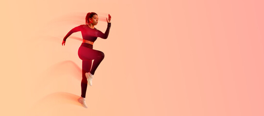Sporty African American lady jumping, having cardio training, wearing black fitwear, exercising...