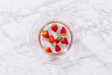 Preparing Strawberries in a Glass Mixing Bowl with Water