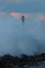 Obraz premium Big stormy wave over old lighthouse. storm at sea, waves crashing against the lighthouse