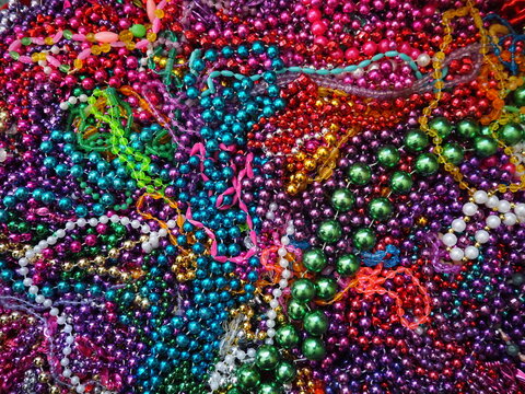 Mardi Gras beads assortment flat lay pile of multicolor parade throws New Orleans street festival necklaces