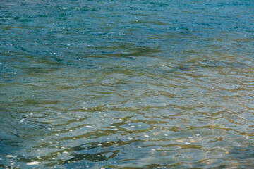 Blue water with ripples on the surface. Defocus blurred transparent blue colored clear calm water surface texture with splashes and bubbles. Water waves with shining pattern texture background.