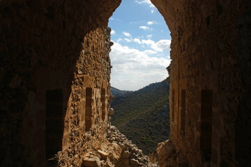 View through stone arch Stone archway framing a mountainous landscape with a partly cloudy sky.