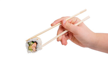 Close-up of a hand using wooden chopsticks to hold a sushi roll with salmon, avocado, and cucumber against a white background.