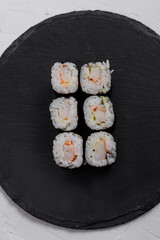 Top view of Six shrimp sushi maki rolls wrapped in nori, served on a black slate plate. A simple and elegant Japanese dish with fresh ingredients and delicate presentation.
