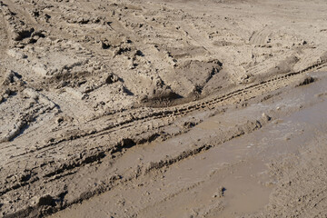 Muddy road with deep vehicle tracks after heavy rain and melting snow, Deep tire tracks in wet, muddy slush, Muddy terrain with tire impressions, challenges of off-road environments
