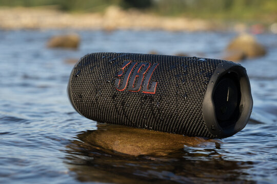LVIV, UKRAINE - SEPTEMBER 8, 2023: JBL Flip 6 Black, portable bluetooth speaker in the water on the river bank