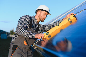 Man worker mounting photovoltaic solar panels. Engineer in helmet installing solar module system. Concept of alternative, renewable energy
