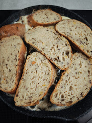 Slices of whole wheat bread frying in butter in a pan for breakfast