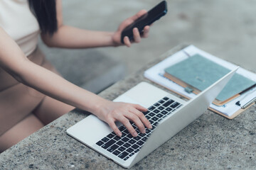 Focused Work: A woman concentrates on her work, typing on a laptop with a smartphone nearby, capturing a moment of productivity and digital connectivity in a modern setting.