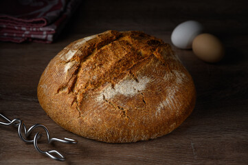 Rustic loaf of bread alongside fresh eggs on wooden countertop ready for a cozy breakfast setting