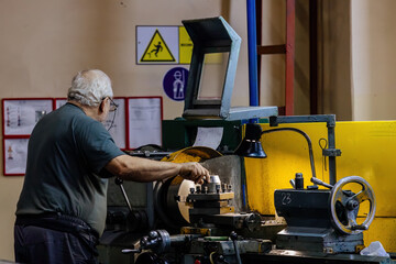 Factory worker working on lathe in metalworking factory