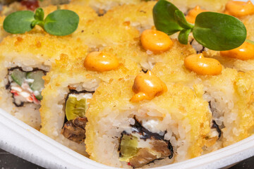 Extreme close-up of sushi rolls with tempura crust, spicy mayo topping, and fresh greens.