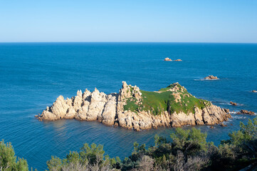 Rocky Mediterranean coastline with a small rocky island. Numerous islets dot this very rocky coastal area.
