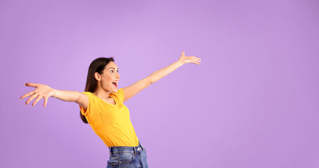 Great Offer. Surprised excited girl with opened arms looking up at copyspace isolated over pastel purple studio wall
