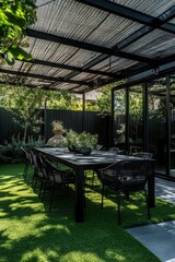 Naklejka premium Modern outdoor dining area featuring black table and chairs surrounded by lush green landscaping in a serene setting during daytime