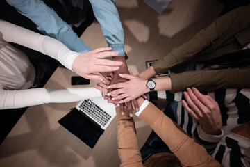 Business people team stacking hands to promote collaboration, inclusion, and equality in the office. Staff huddles together, concept of solidarity, cooperation, and teamwork in a supportive workplace.