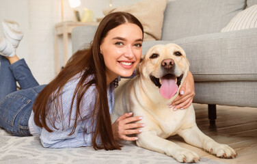 Happy Person. Portrait of positive woman enjoying spending time with her pet at home in living...