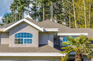 Top of luxury house with shingle roof, red and yellow trees and nice windows in Summer in...