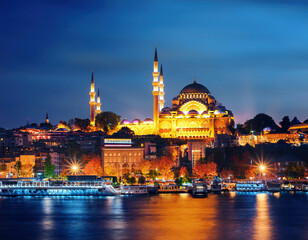 Obraz premium The illuminated Suleymaniye Mosque in Istanbul reflects beautifully on the Bosphorus waters under a deep blue evening sky during Ramadan Kareem.