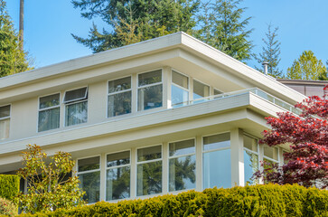 Top of luxury house with shingle roof, red and yellow trees and nice windows in Summer in Vancouver, Canada, North America. Day time on June 2024.