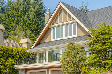 Top of luxury house with shingle roof, red and yellow trees and nice windows in Summer in Vancouver, Canada, North America. Day time on June 2024.