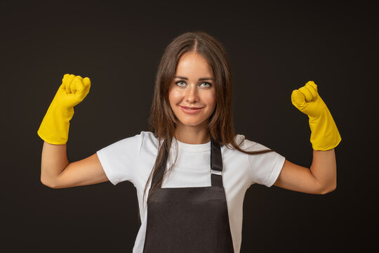 young happy housewife in apron and rubber gloves raised two fists up, joy of victory concept