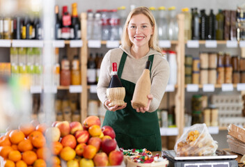 Positive female seller offers to buy bottles of wine in supermarket