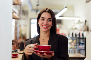 Businesswoman smiling and holding a red cup of coffee in a cafe