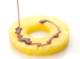 Drizzling chocolate sauce over fresh pineapple slice on white background