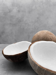 Two halves of fresh coconut resting on gray surface. Copy space, banner