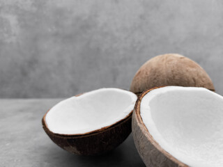 Two halves of fresh coconut resting on gray surface. Copy space, banner