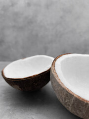 Two empty coconut halves resting on gray surface. Copy space, banner