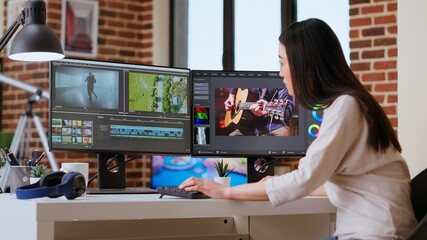 Freelancer asian woman video creator works on a movie project, multitasking with dual monitors, editing software and a color wheel in her home workspace. Film editing industry. Camera B.