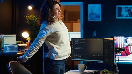 Programmer doing software quality assurance, stretching arms behind back after reading source code,...