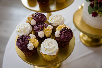 Elegant purple and white frosted cupcakes on gold display plates for wedding reception