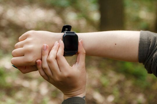 Hiker checking her smartwatch while enjoying a peaceful walk through the lush woods, blending modern technology with the tranquility of nature and enhancing her outdoor experience - Powered by Adobe