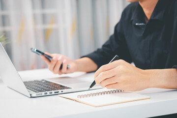 A close-up of a hand holding a pen, writing on a document for professional purposes.