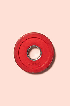 Red weight plate gym equipment on a pink background